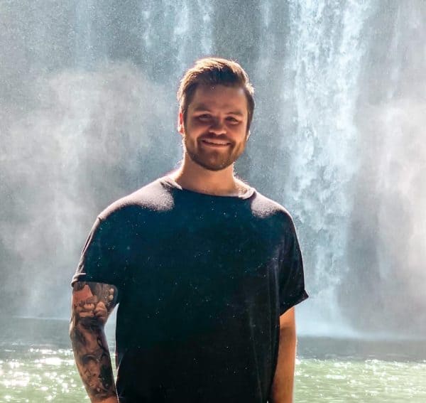 Daniel standing in front of a waterfall.