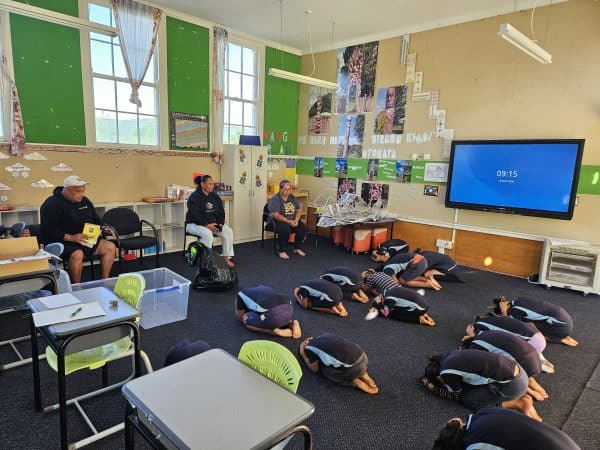 Tamariki at Te Kura ā-Iwi o Torere practicing 'taka, uhi, mau tonu' (drop, cover, hold) nā Cassino Akuhata, Ngāti Haka-Patuheuheu. Overseen by Kelvin Tapuke, Massey University, Wency Rewi – Tumuaki, Te Kura ā-Iwi o Torere and Elsa Kupa – Kaiako, Te Kura ā-Iwi o Torere. Photo credit: David Johnston, March 2024.