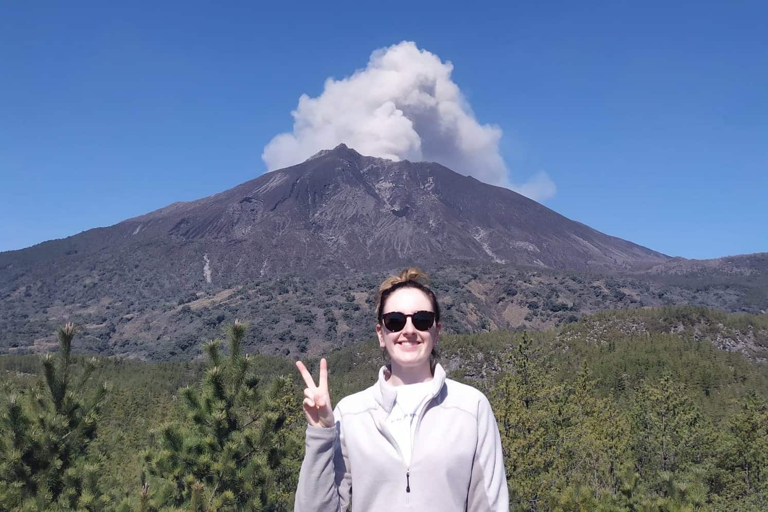 Emmy Scott standing in front of a volcano.