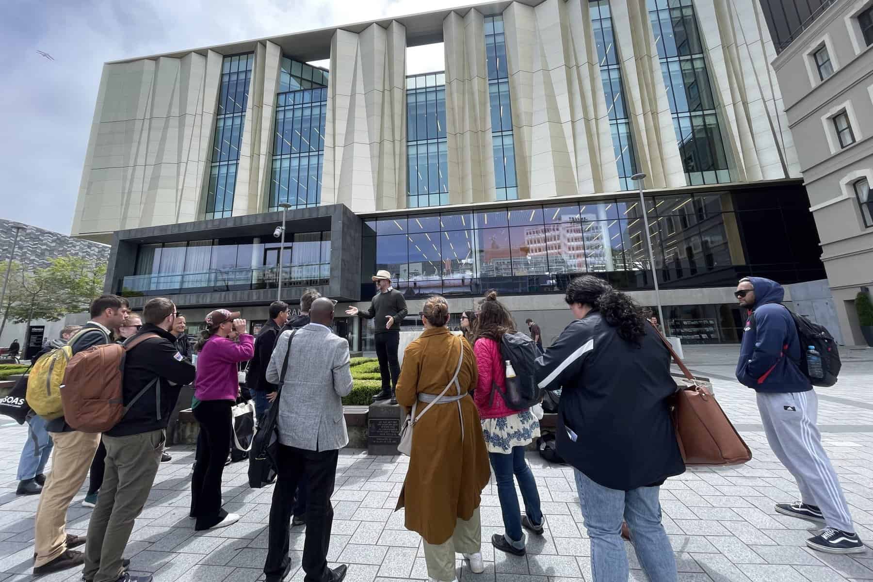 Field trip attendees listening to a talk outside buildings in Ōtautahi Christchurch
