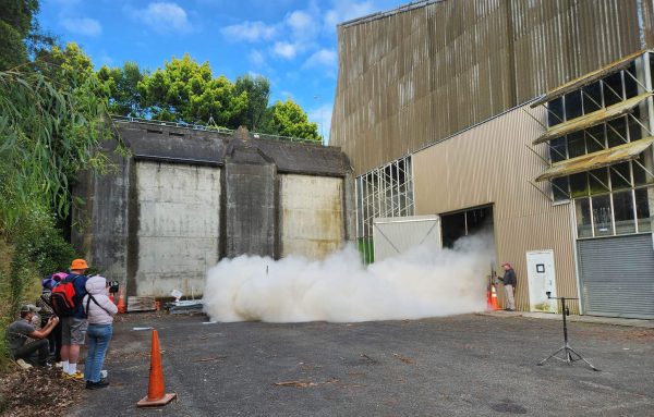 A cloud of ash exiting the old boiler house as part of an experiment at the Pyroclastic flow Eruption Large-scale Experiment (PELE) facility at Massey University.